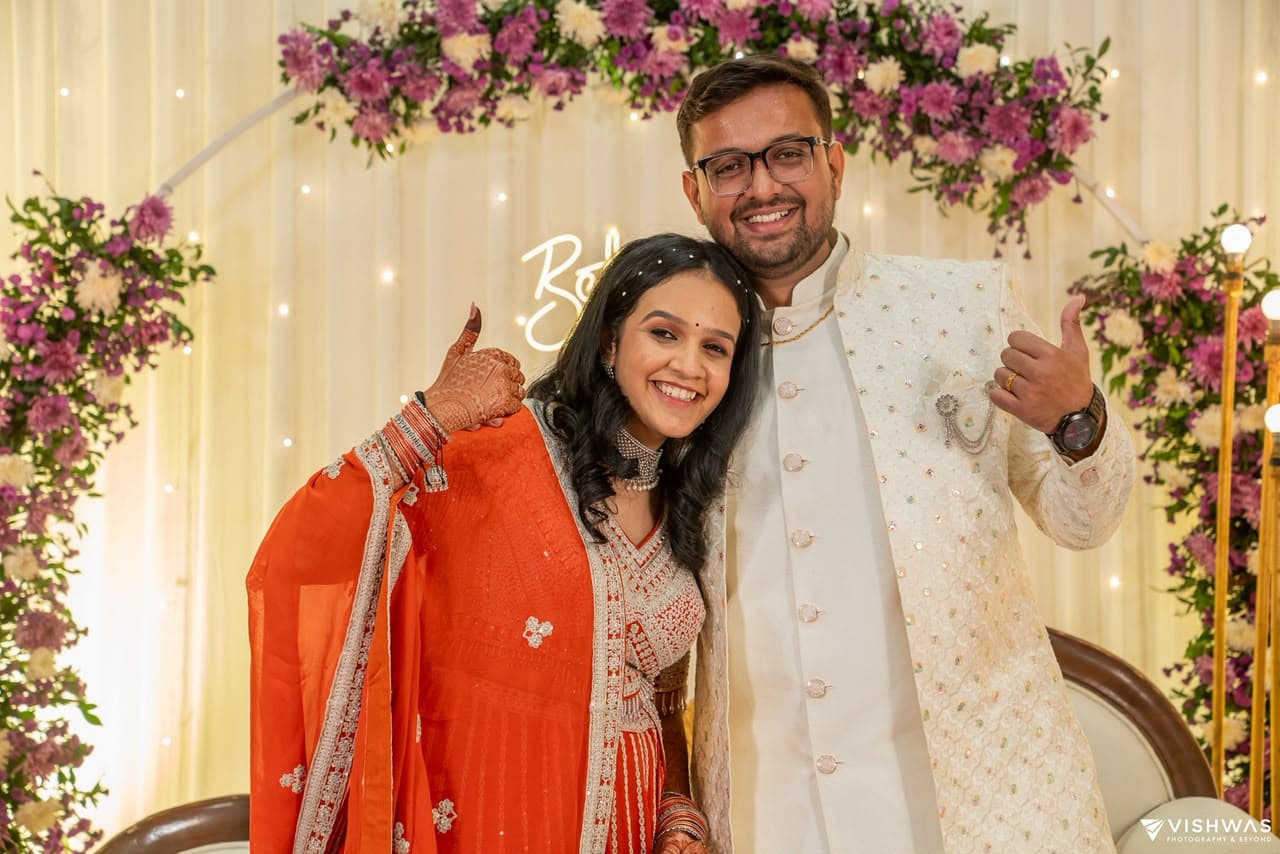 Newlyweds Dhrumil & Kajal celebrating under a floral arch